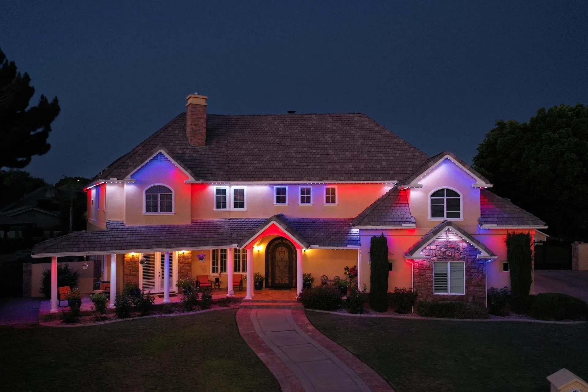 Red, blue, and white lights outlining the roofline of a two-story home at night