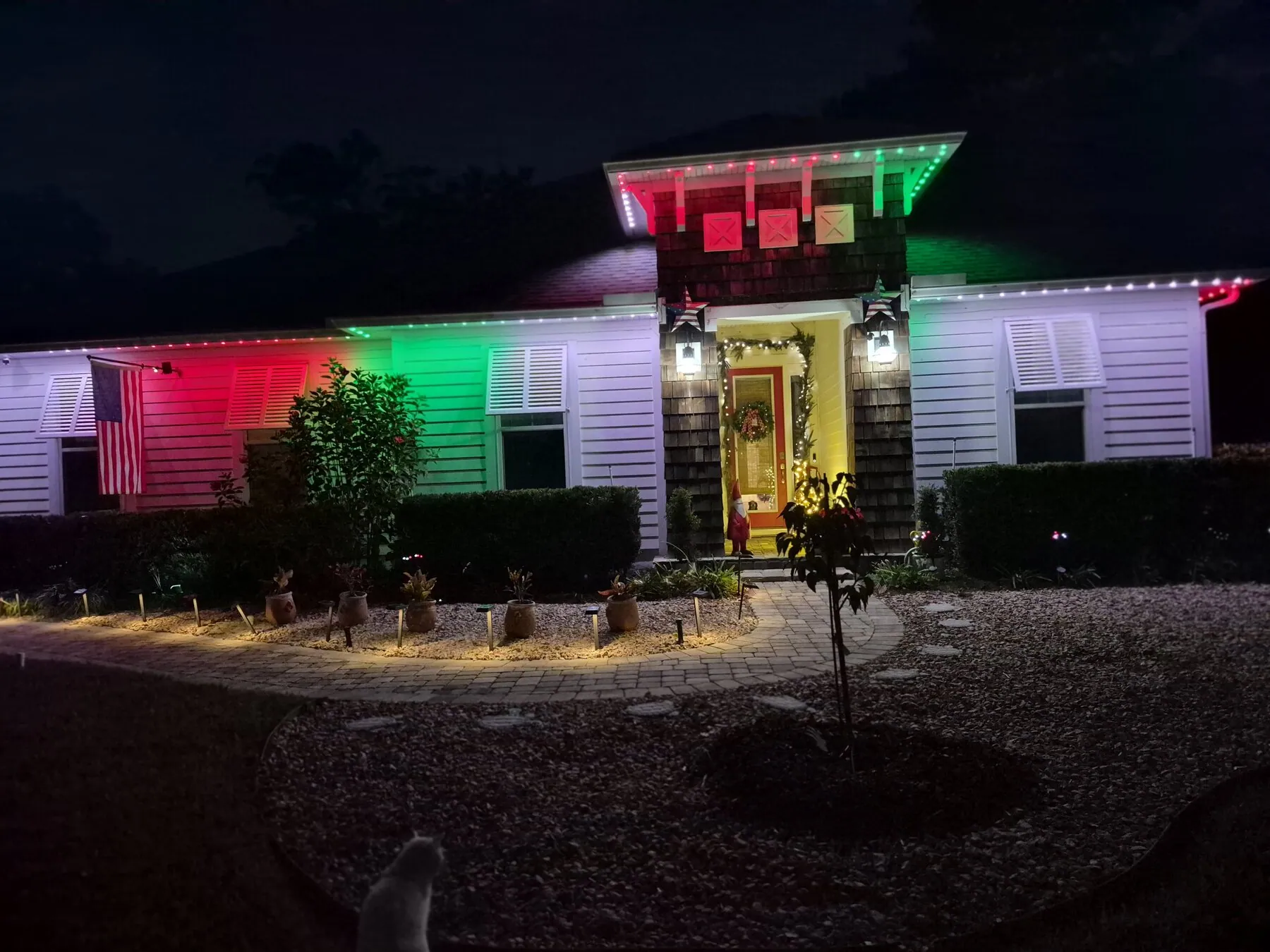 Red and green holiday lighting across a home's front exterior