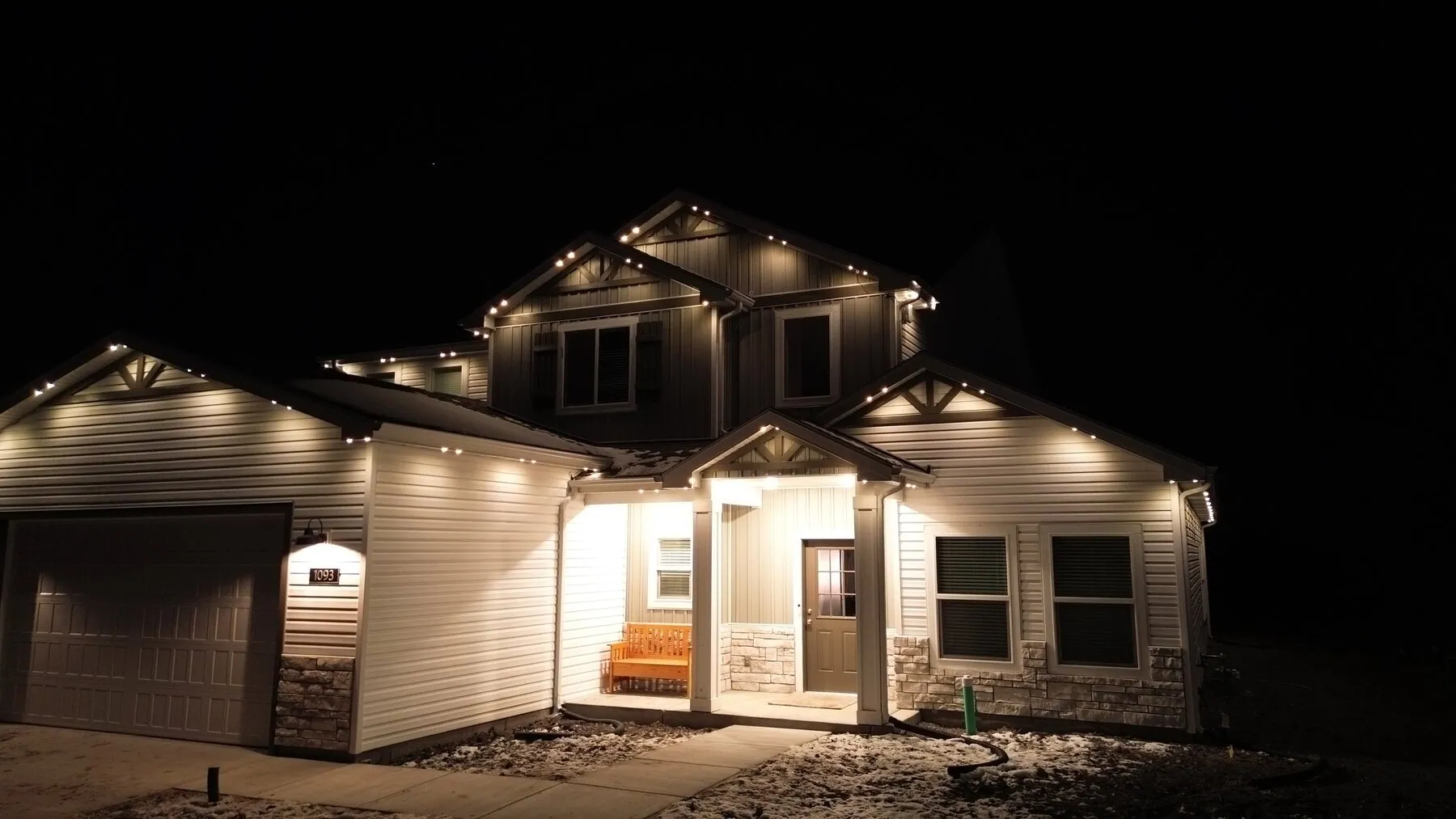 Warm lighting on a two-story home's front-facing rooflines