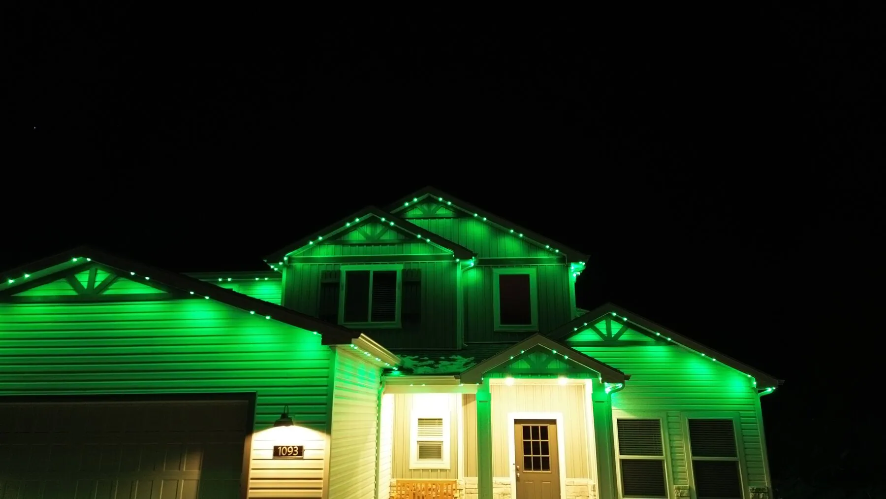 Green lighting on a home's garage and upper roofline