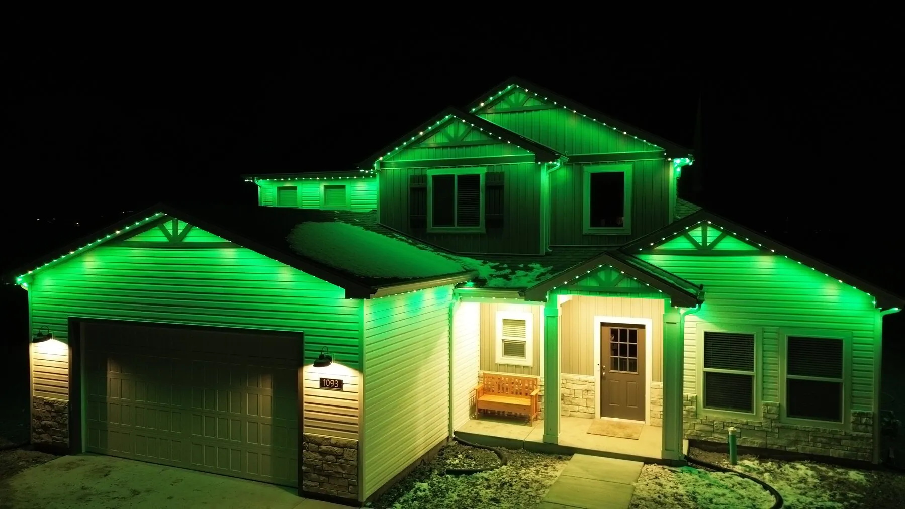 Green lighting illuminating a home's gables and front entry