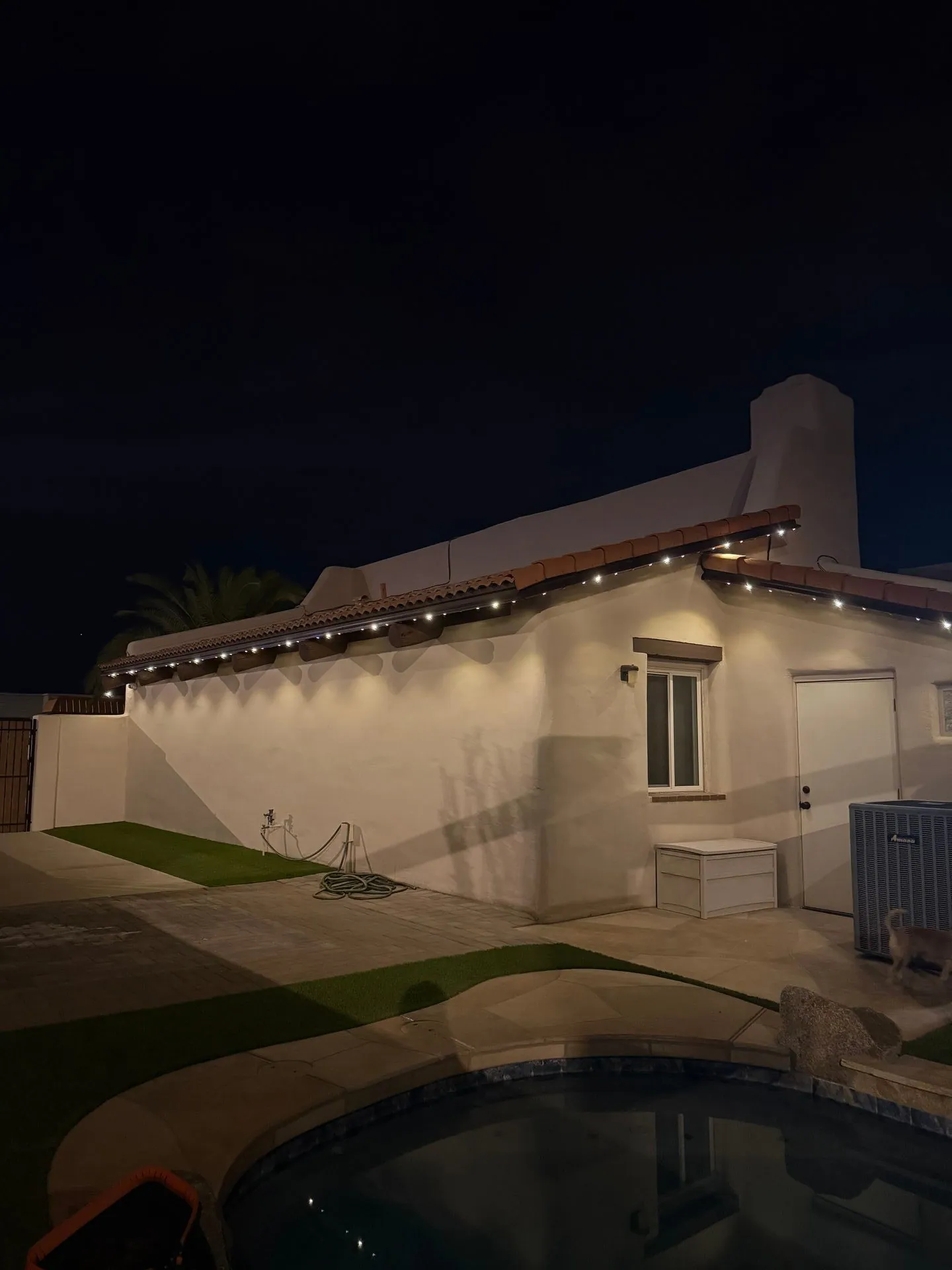 Backyard wall lighting on stucco home with pool