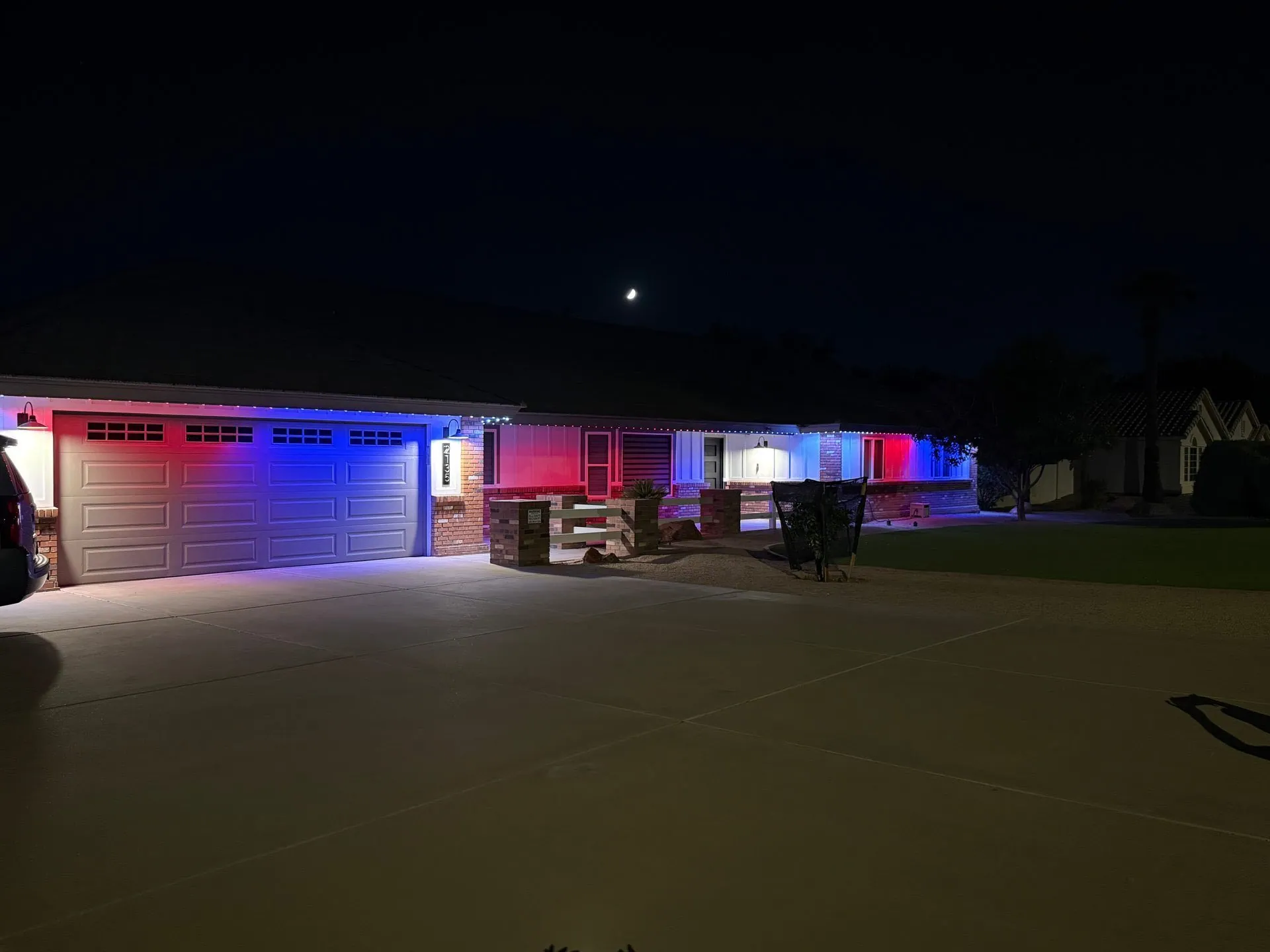 Red, white, and blue lights illuminating the front of a single-story home at night