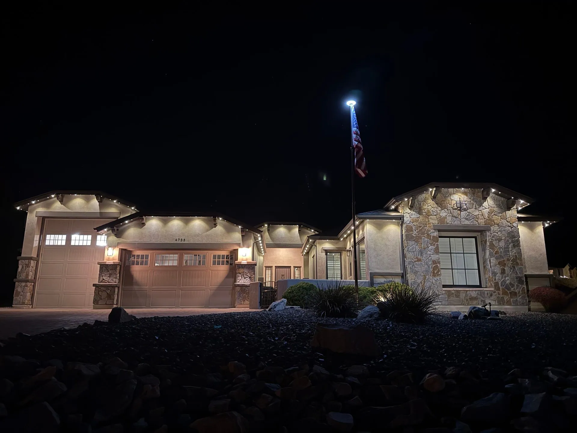 Stone and stucco home with permanent downlight installation