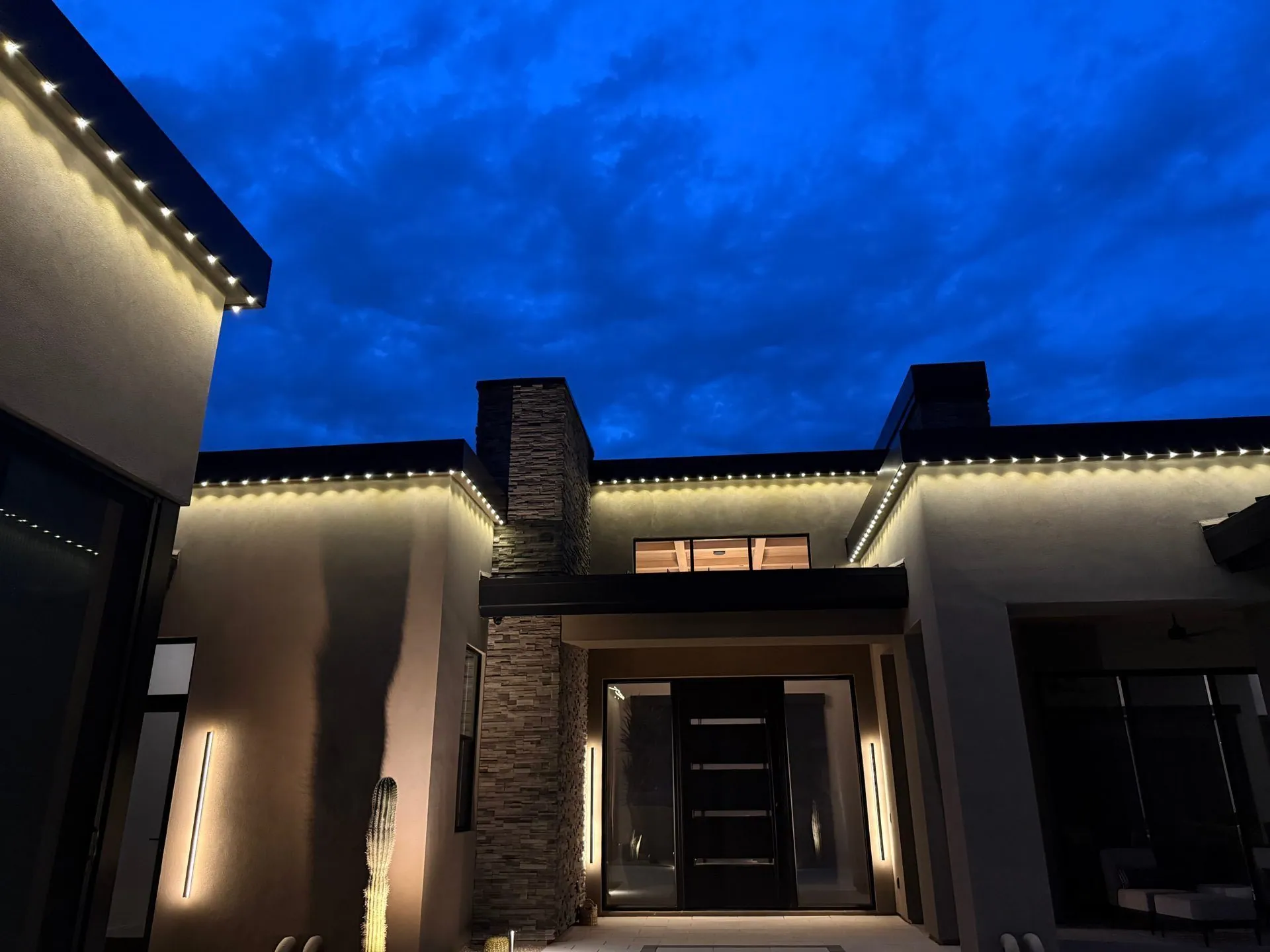 Modern home with permanent roofline lighting at dusk
