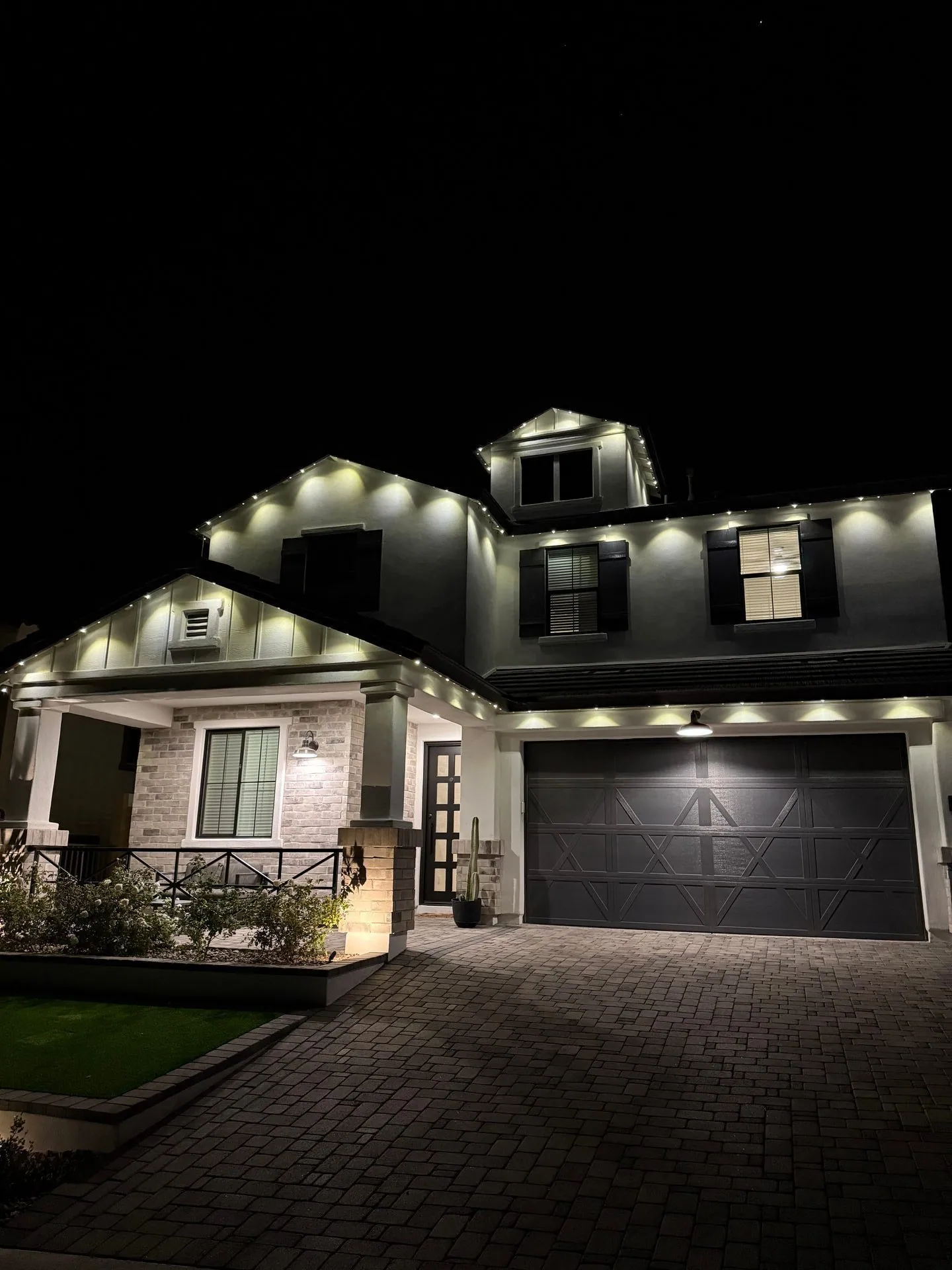 Two-story home with warm white permanent lighting at night