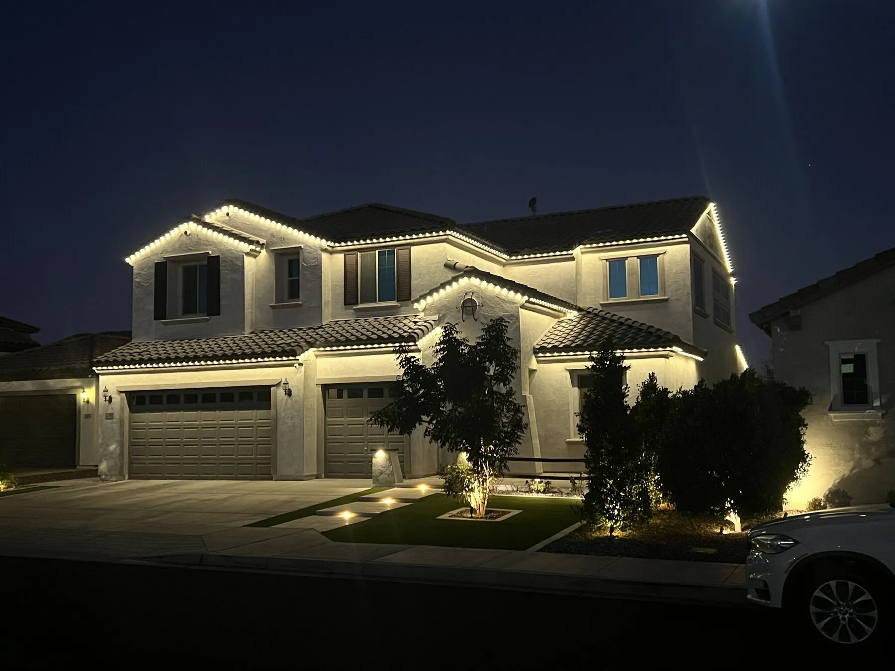 Warm white roofline lighting on a two-story home at night