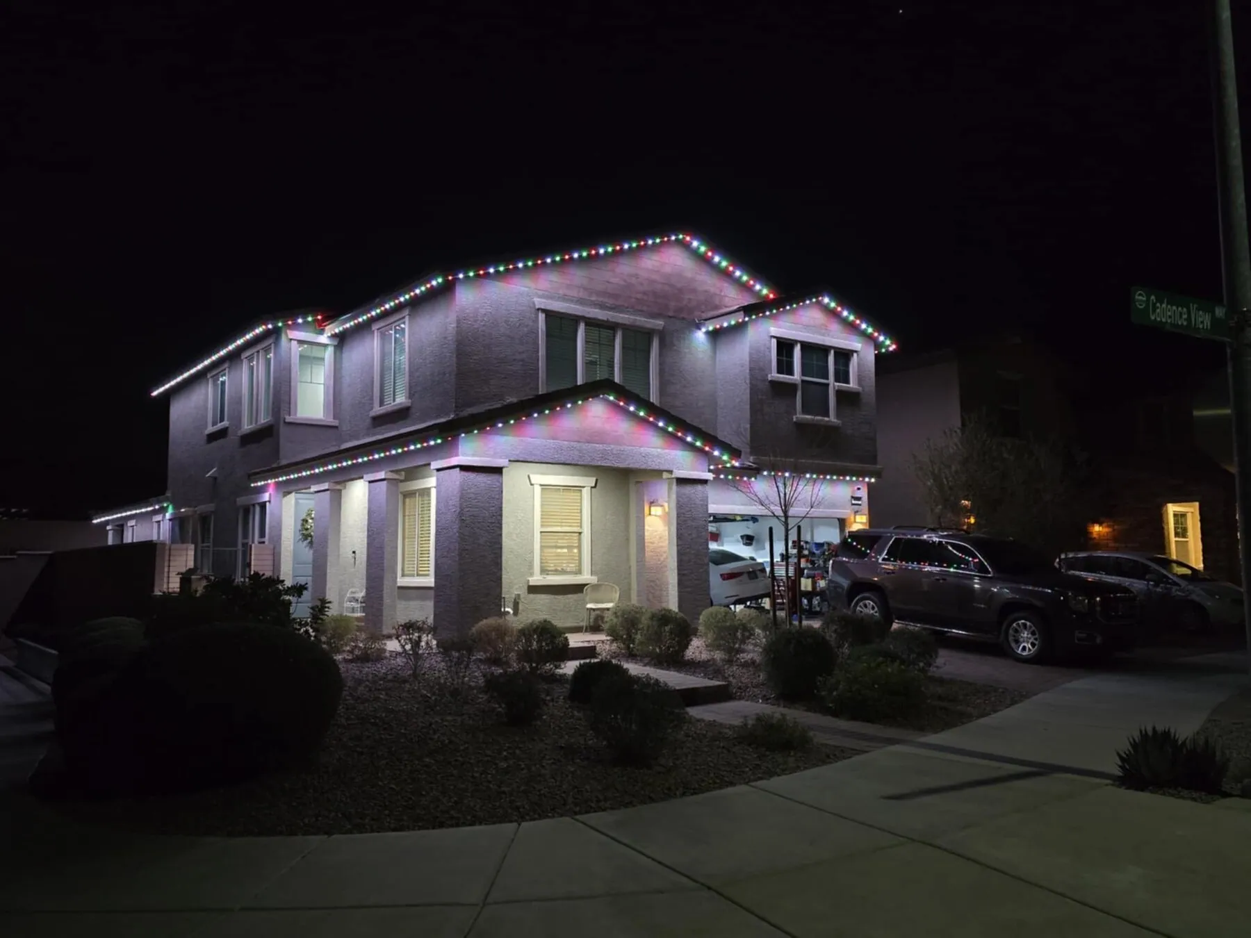 Multicolor permanent lighting on a two-story home's roofline