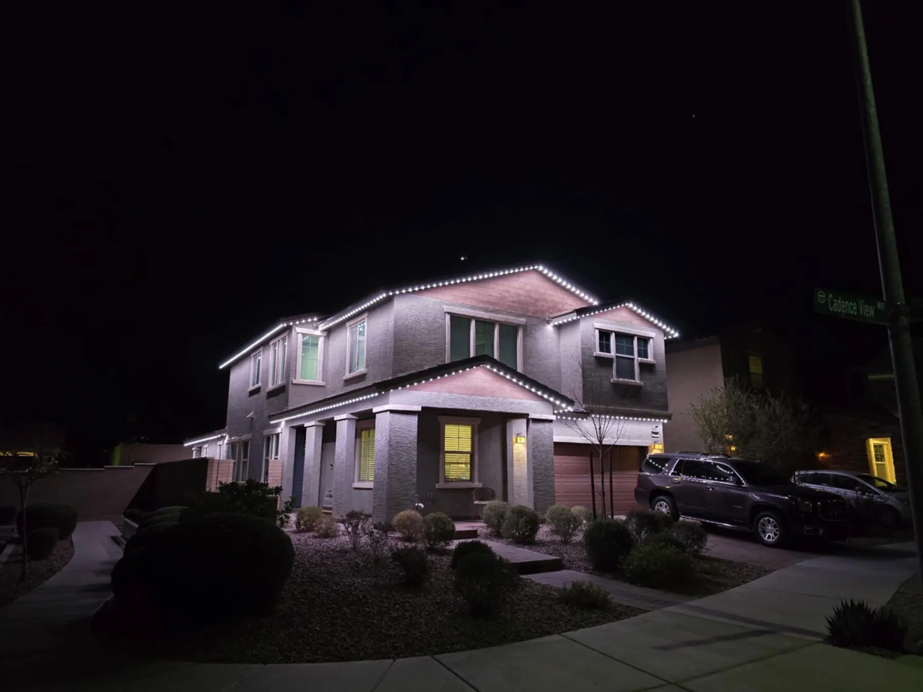 White roofline lights on a two-story home at night
