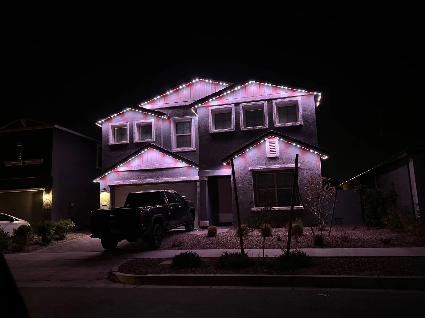 Pink and purple lighting on a home's roofline and entry