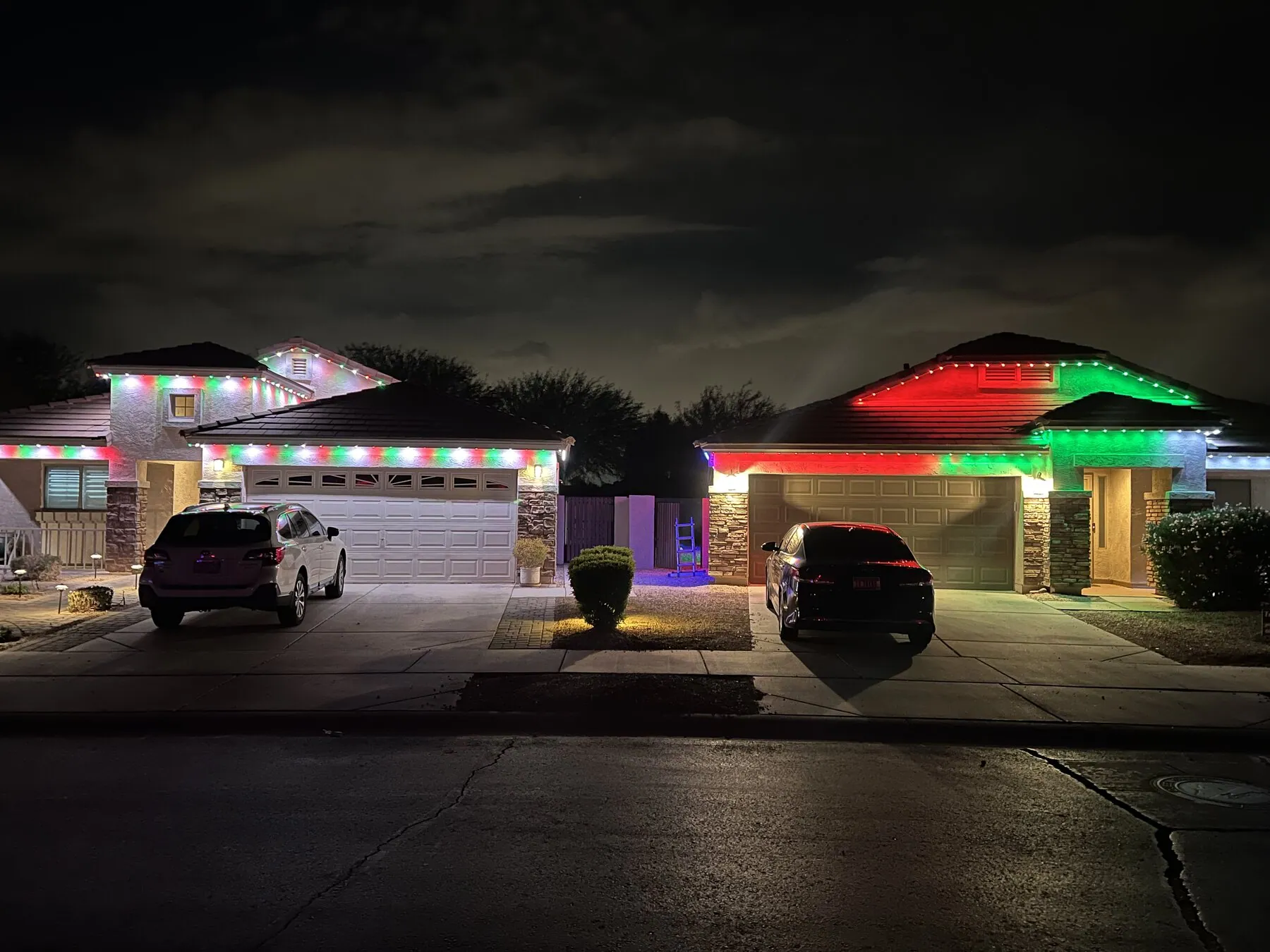 Red and green holiday roofline lighting on neighboring homes