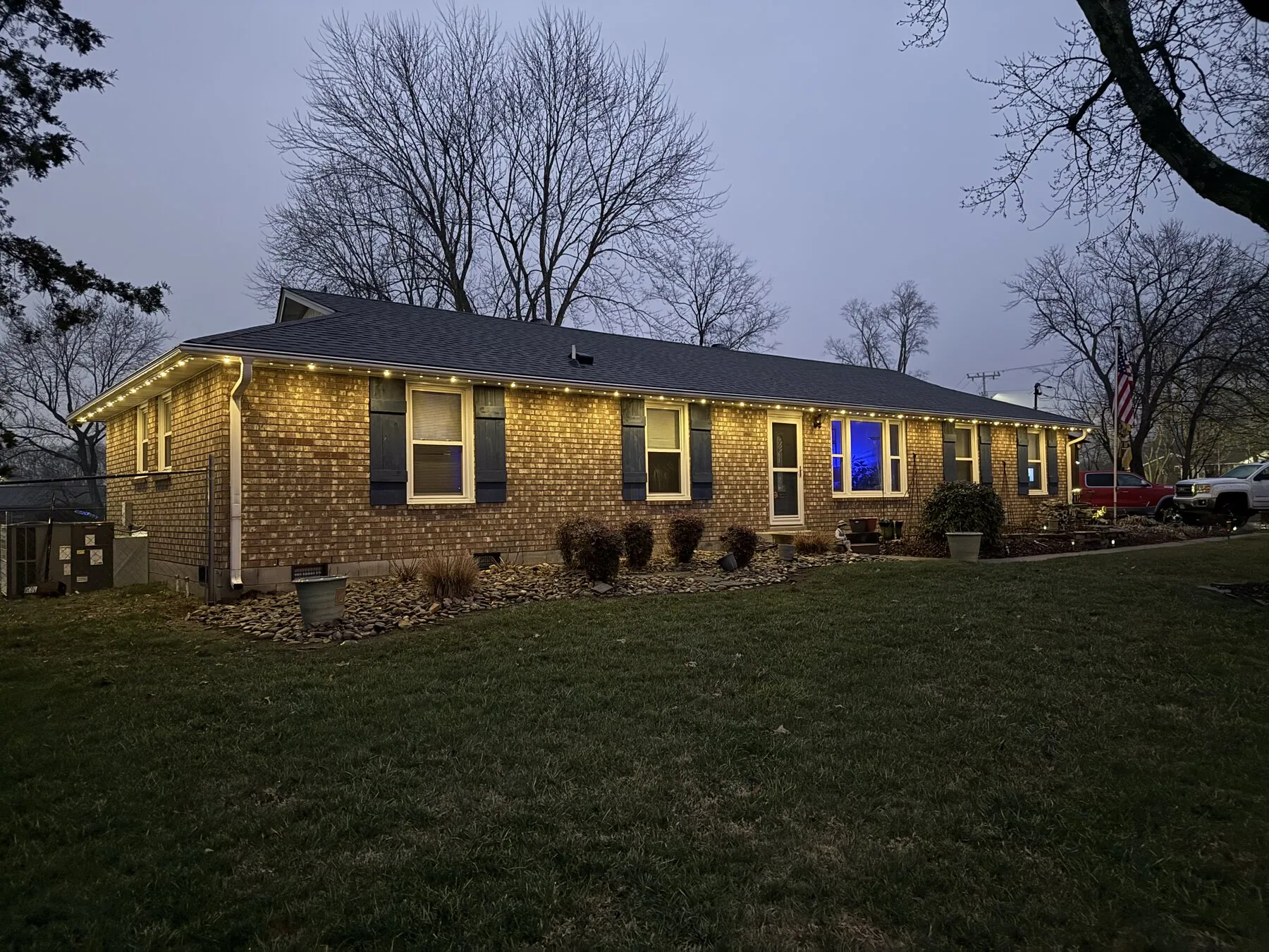 Warm roofline lighting on a single-story home at dusk
