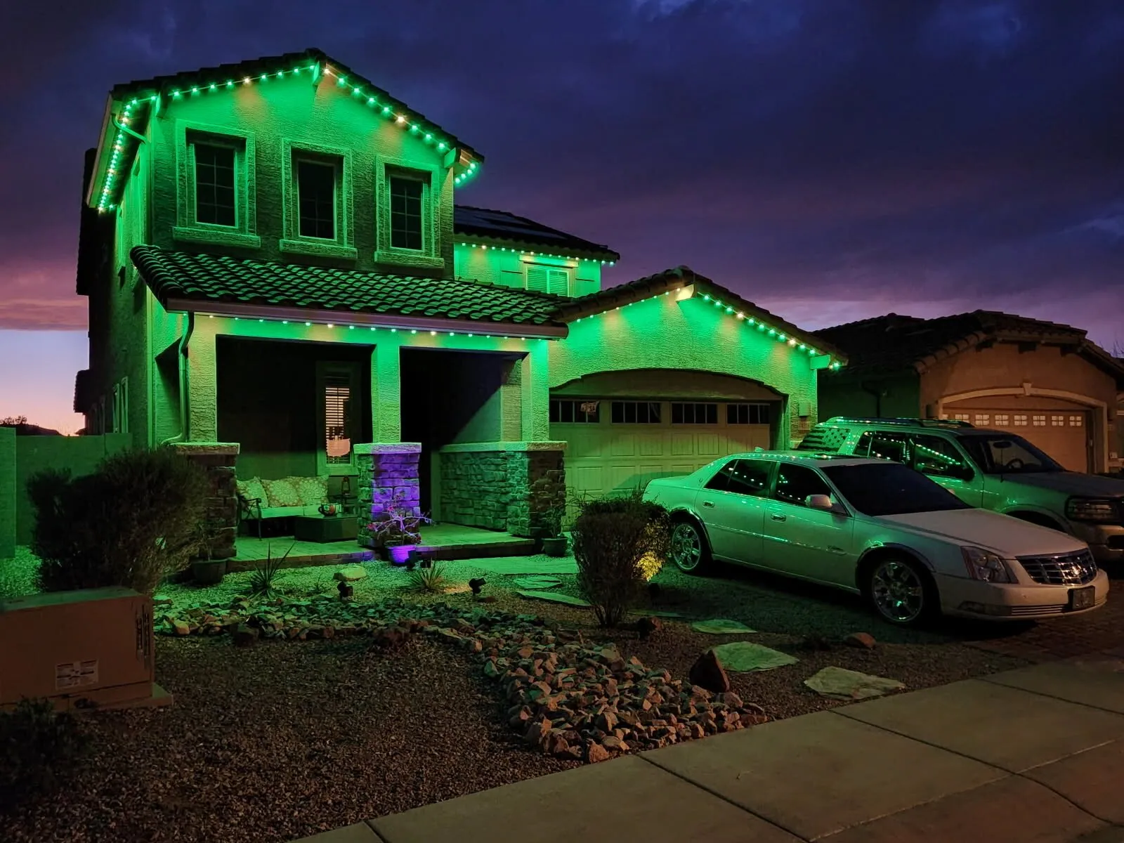 Green permanent lighting on a two-story home at dusk