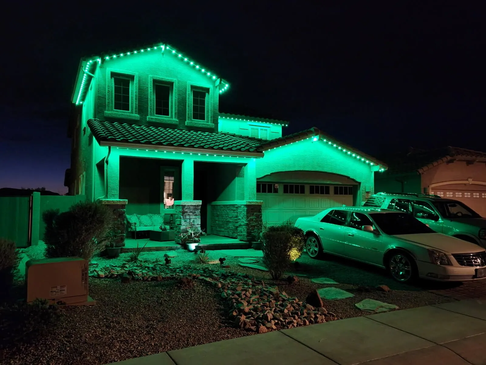 Green roofline lighting on a two-story home at night