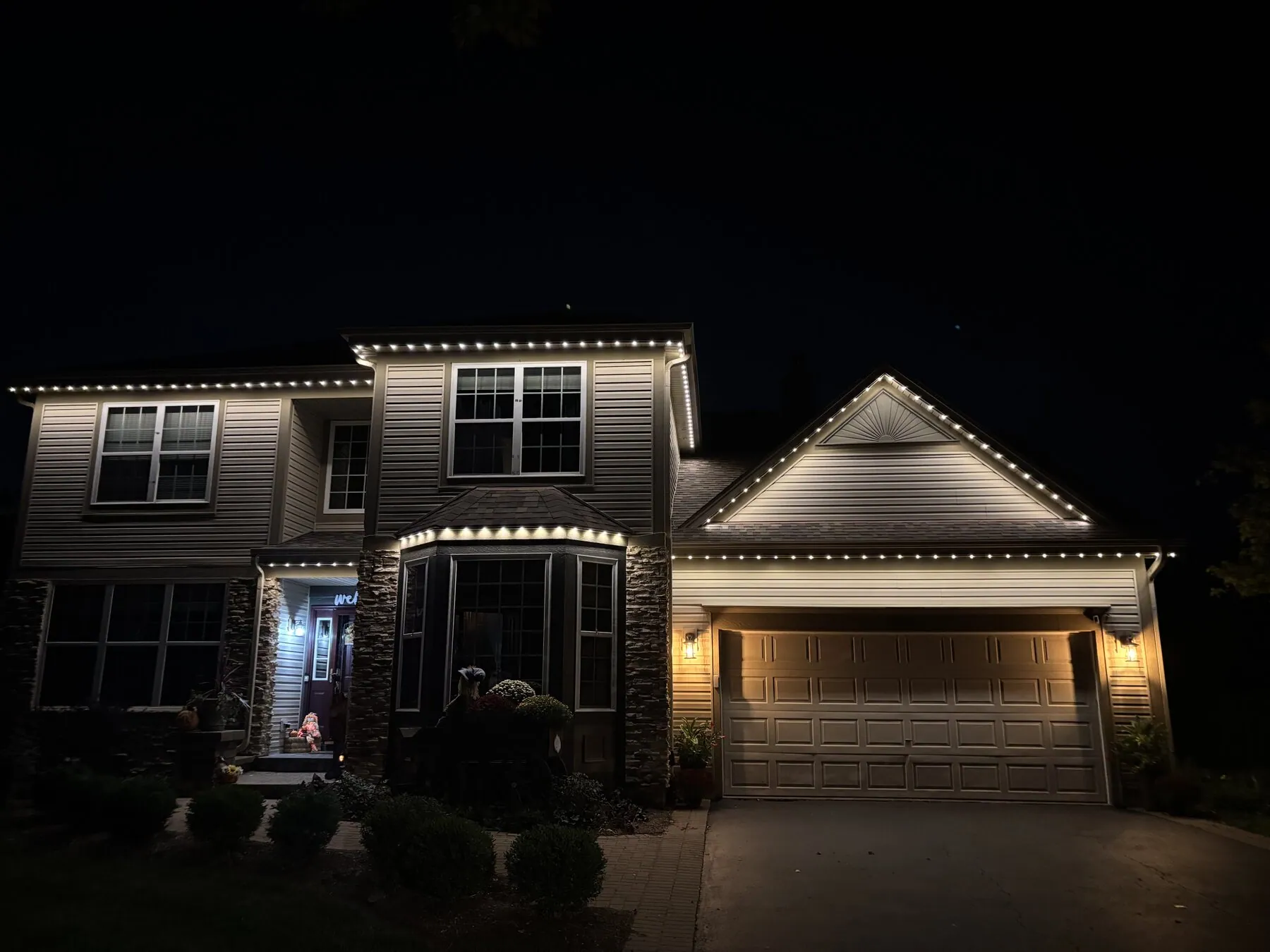 Warm white lighting on a two-story home and garage