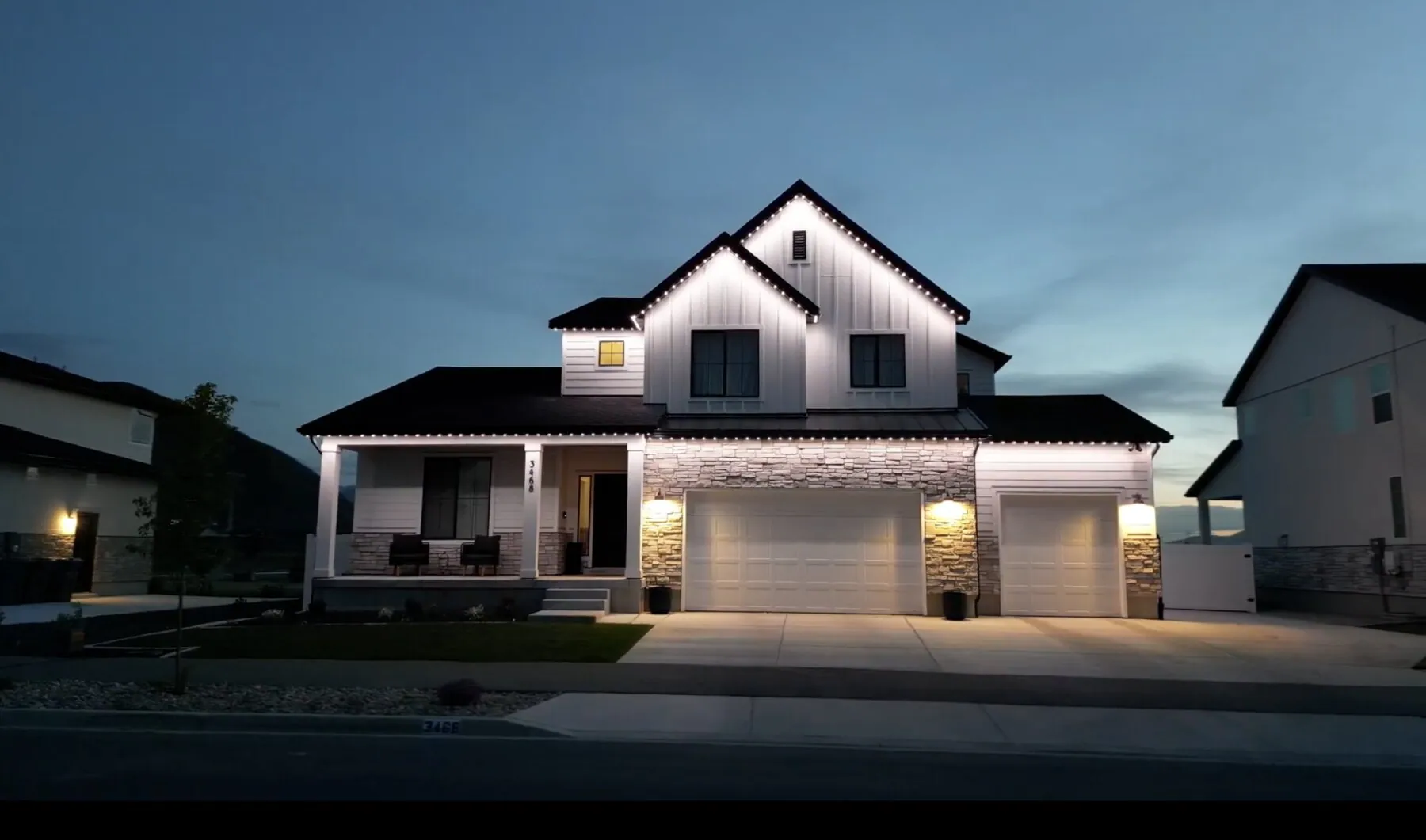 White roofline lighting on a modern farmhouse at dusk