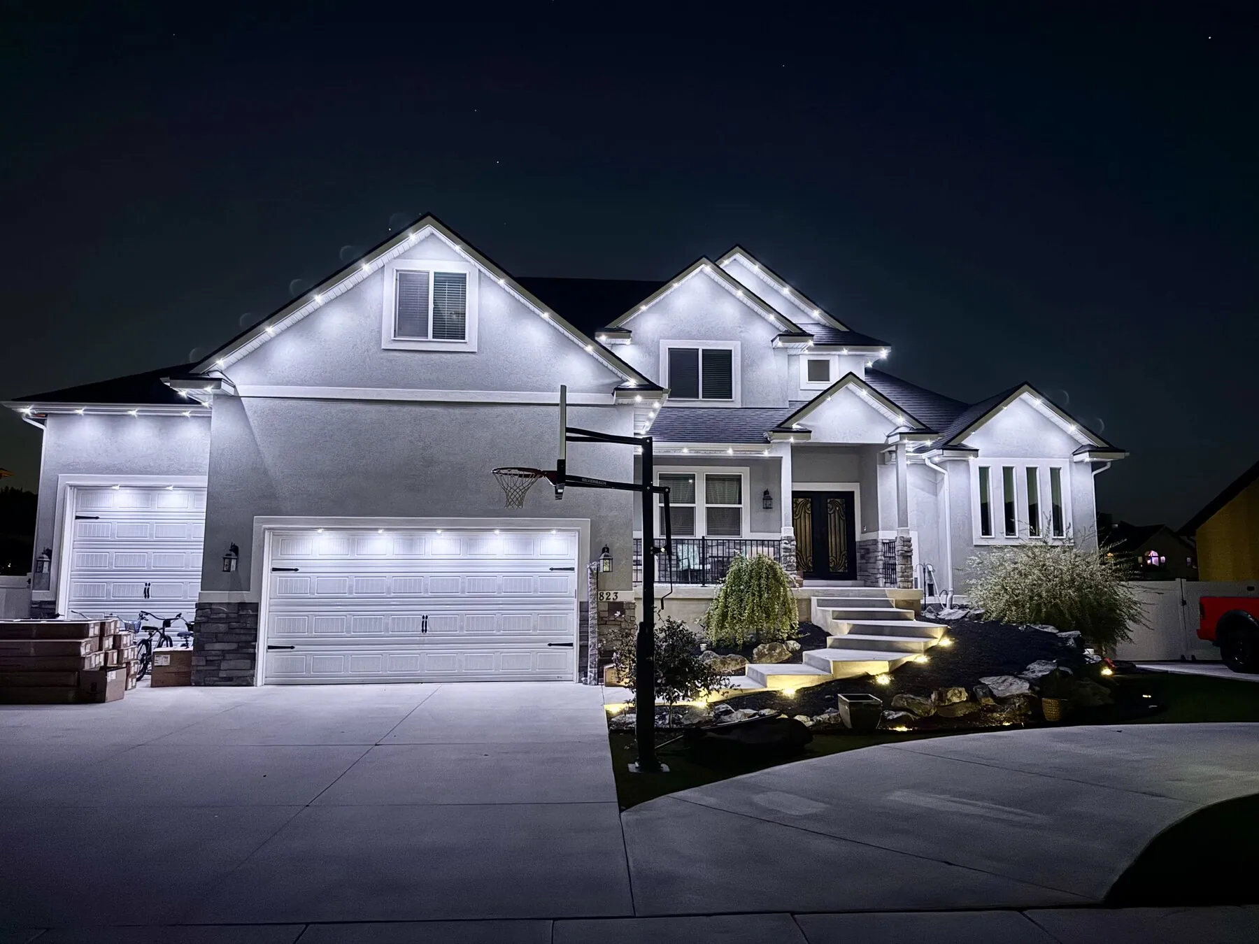 Cool white permanent lighting on a two-story home at night