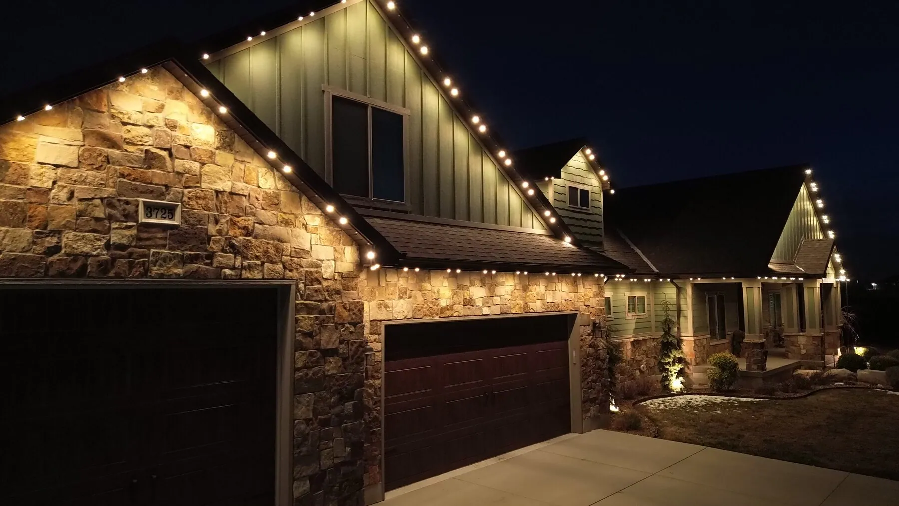 Close view of warm roofline lighting above stone garage walls