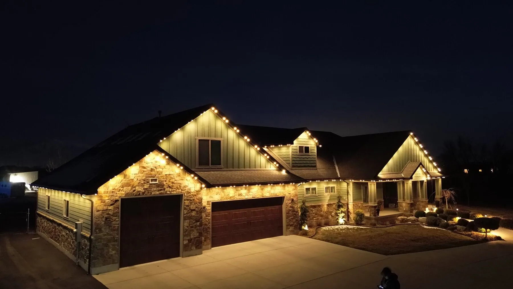 Warm white lighting across a home's gables and garage rooflines