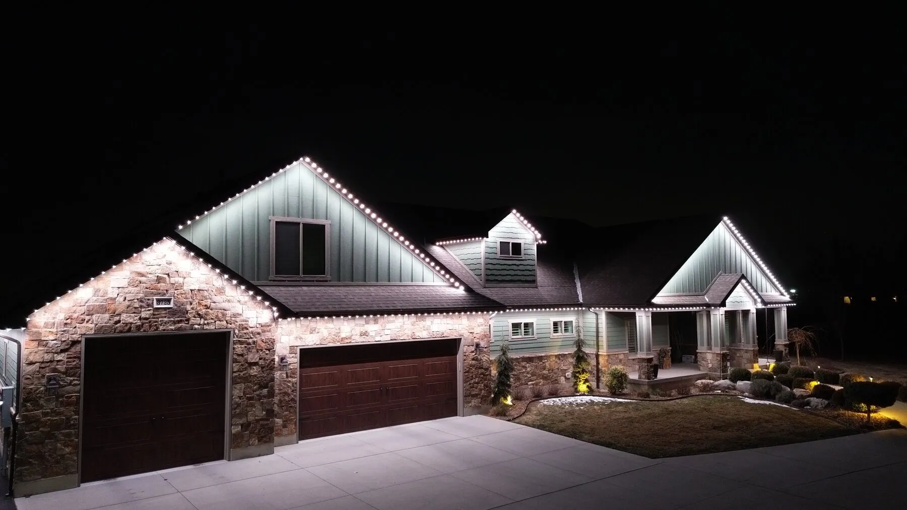 Bright white roofline lighting on a stone and siding home