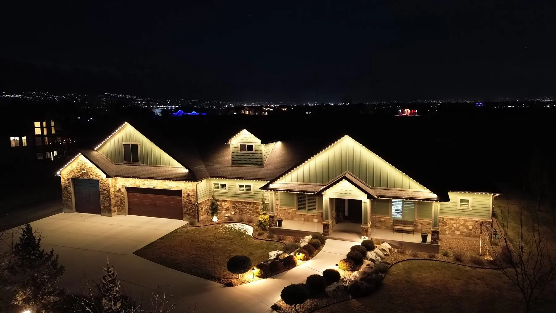 Warm roofline lighting on a home viewed from above at night