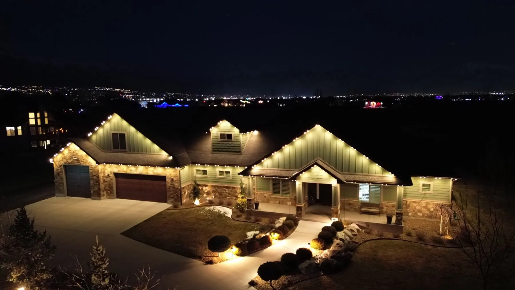 Aerial view of warm white lighting across a home's front exterior
