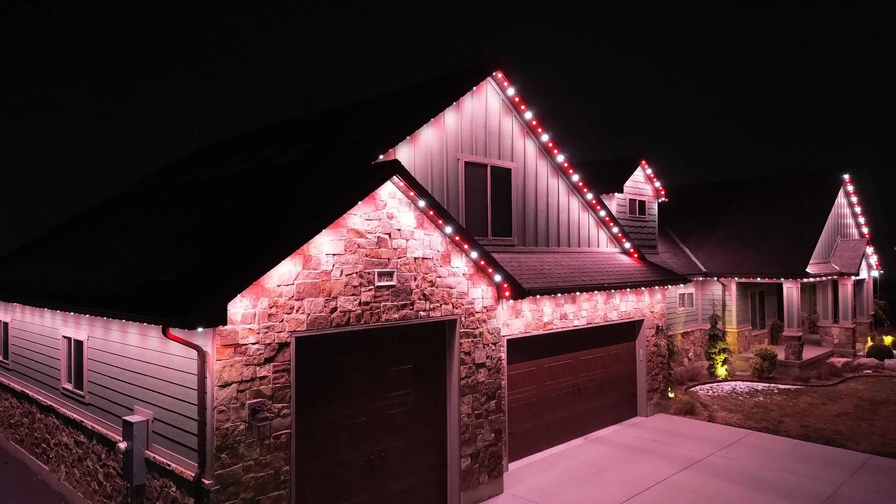 Pink and red permanent lighting on a home's roofline