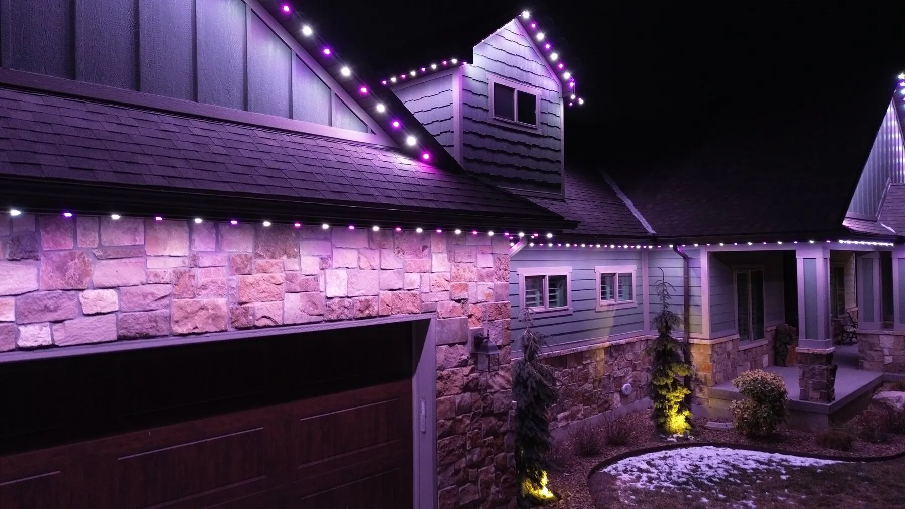 Close view of violet permanent lights along a garage and dormer