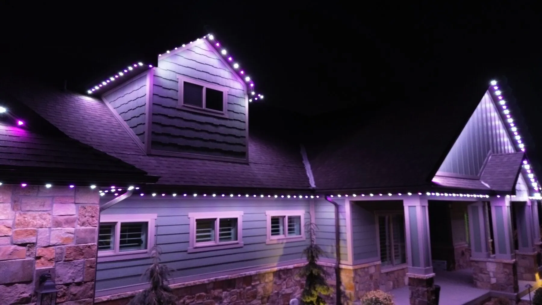 Close view of violet roofline lighting on a dormer and porch