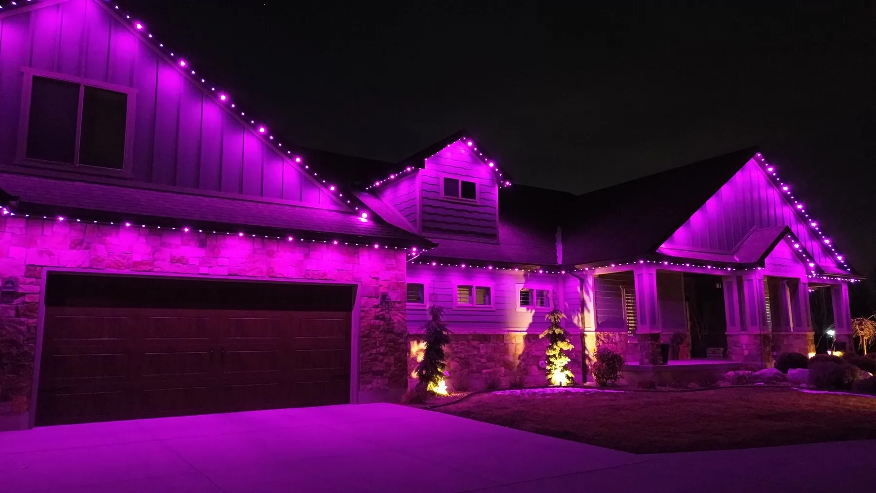 Magenta lighting across a home's gables and entry