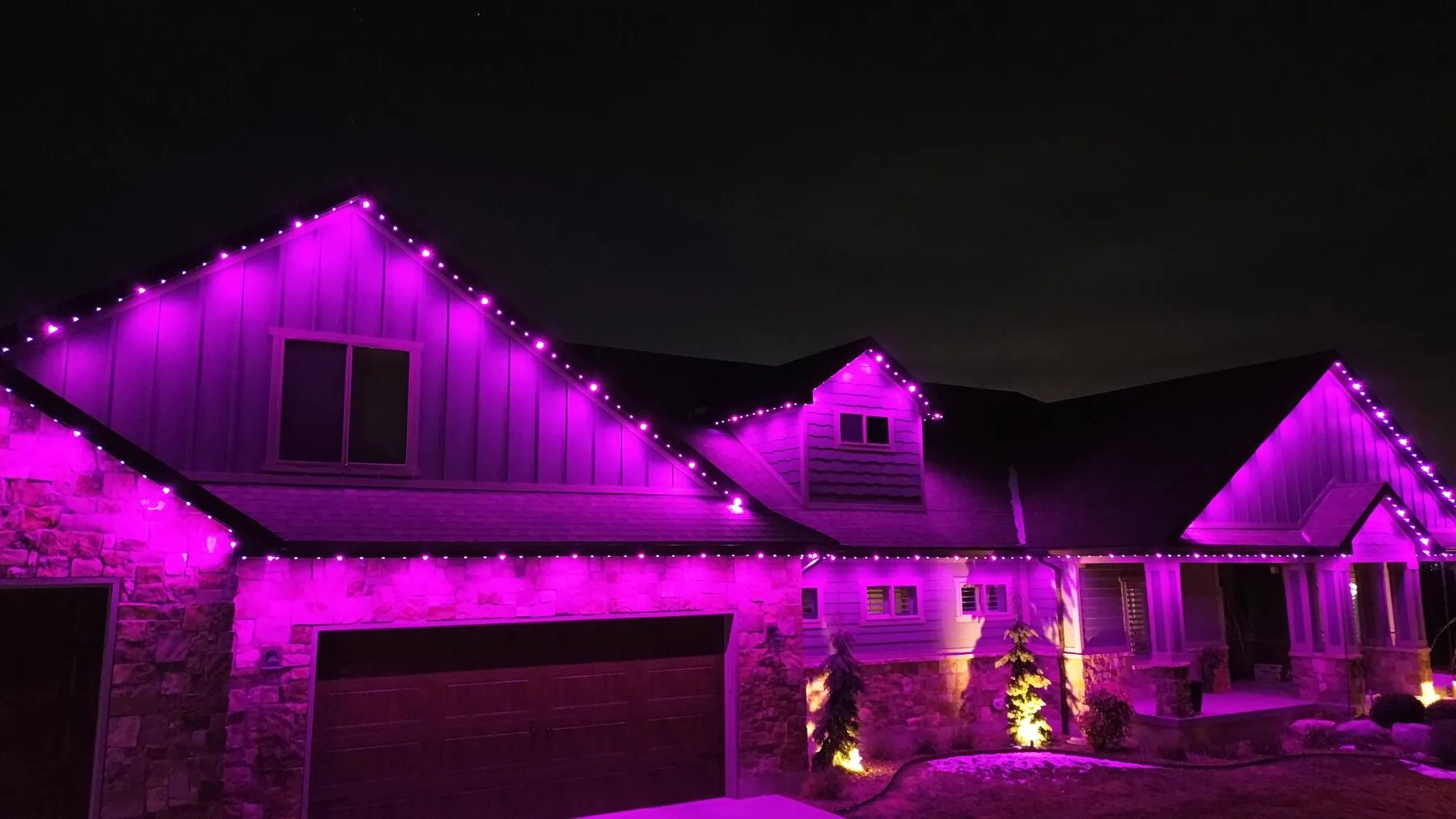 Pink and purple lighting on a gabled home at night