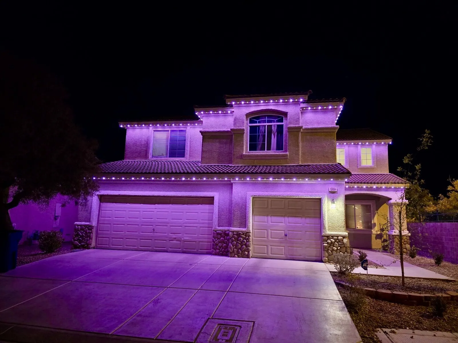 Purple accent lighting on a two-story home and garage