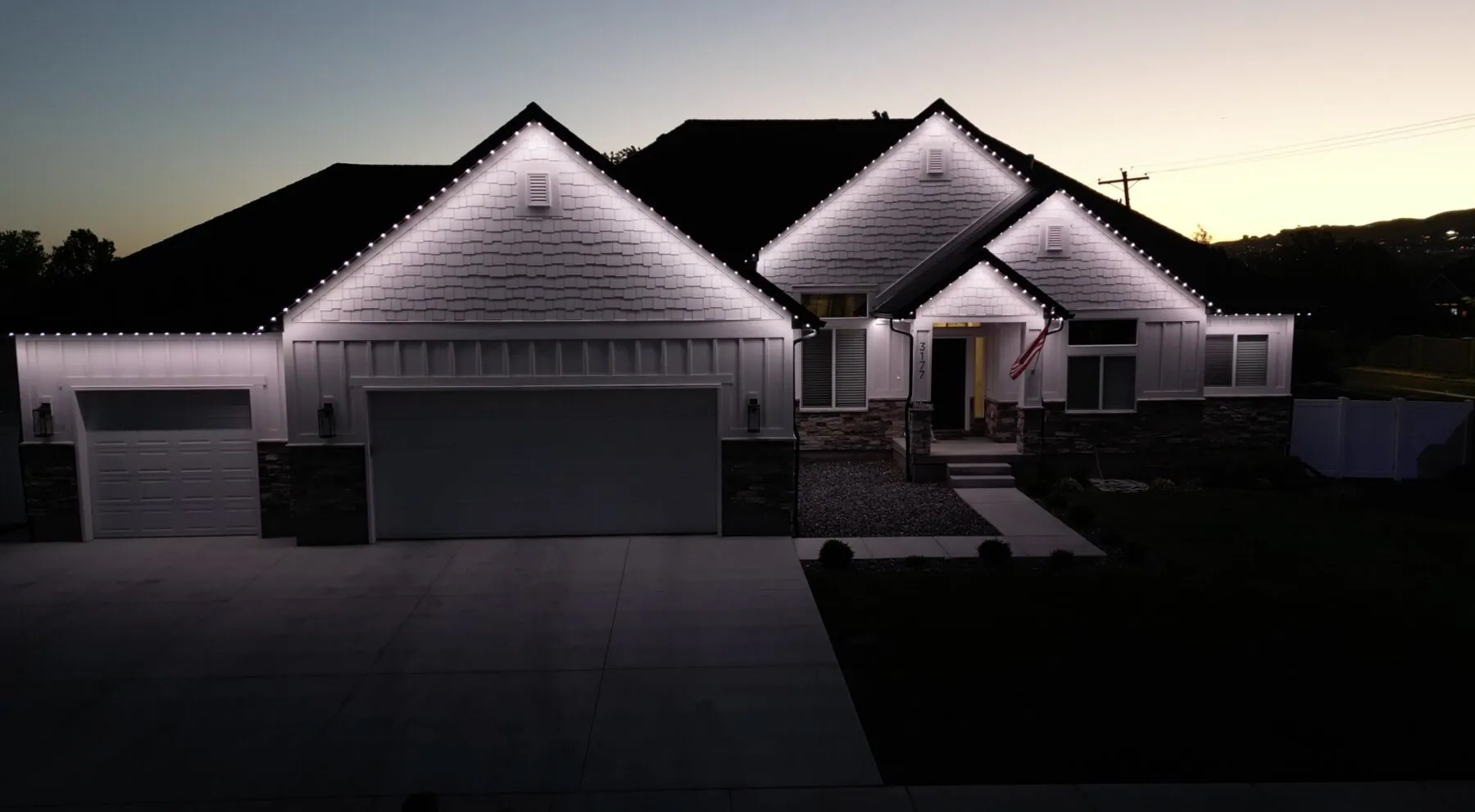 Cool white roofline lighting on a single-story home at dusk