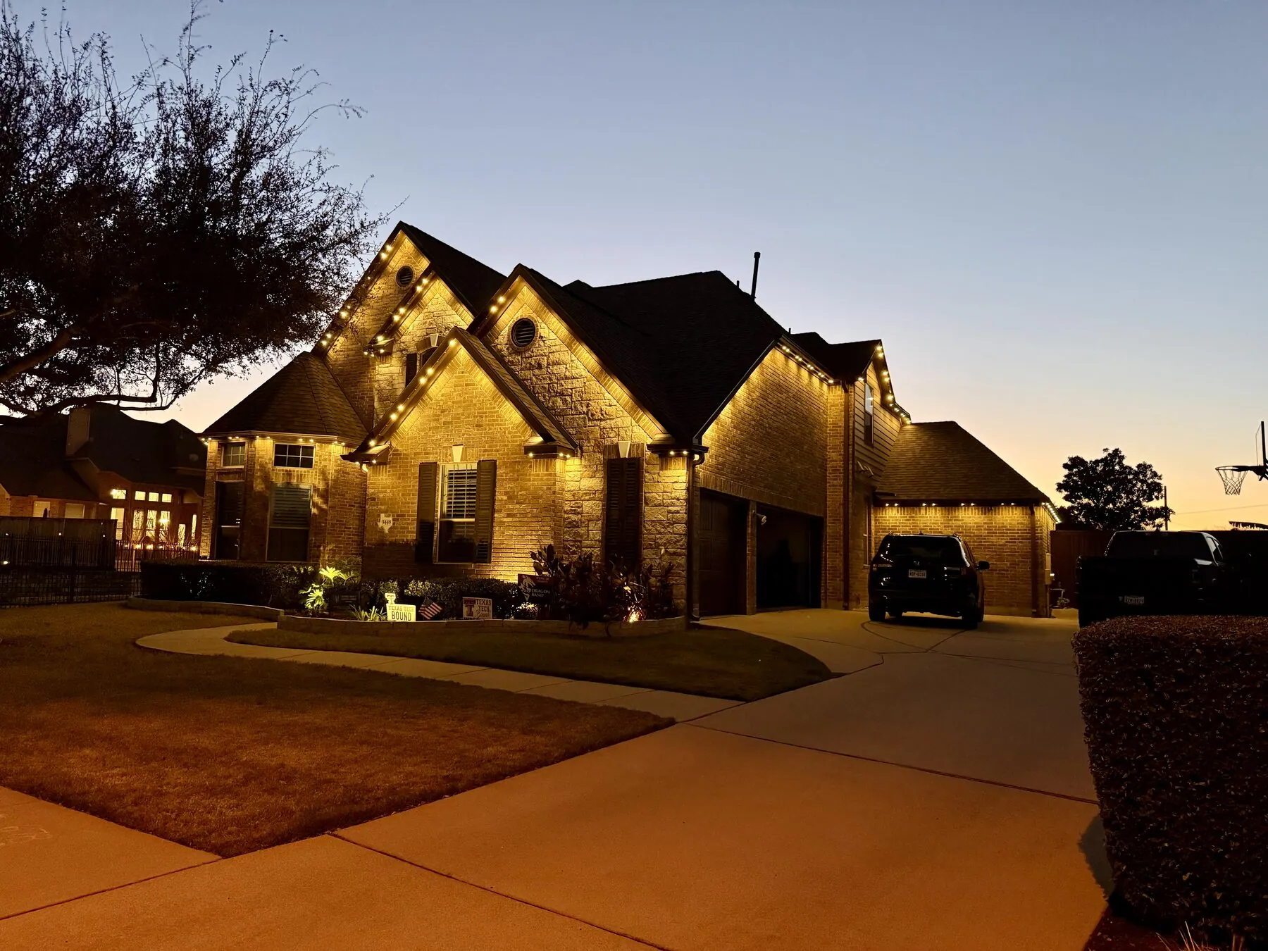 Warm roofline lighting on a brick home at sunset